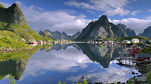 houses beneath body of water near mountains under cloudy sky