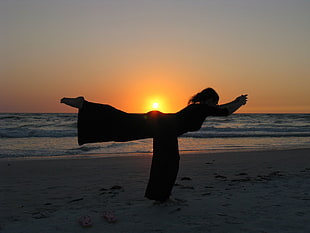silhouette of woman doing yoga during sunset on beach