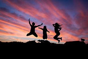 silhouette image of three persons jumping