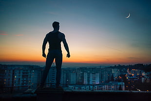 silhouette of man standing on buildings digital wallpaper