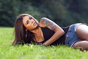 woman wearing black shirt and blue shorts lean on grass field