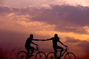 silhouette of couple riding bikes