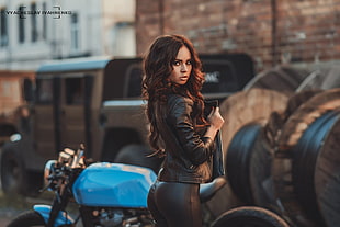 woman wearing black leather motorcycle jacket near blue sports bike