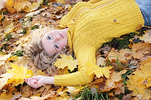 woman in yellow sweater lying on maple leaves during daytime HD wallpaper