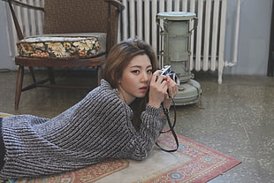 woman wearing a gray sweater holding a camera