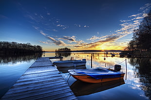 two orange and white motor boats beside brown wooden lake dock during golden hour HD wallpaper