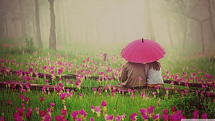 two people sitting on brown surface surrounded by pink flowers