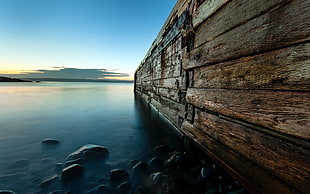 photography of brown wooden groynes under blue sky during daytime
