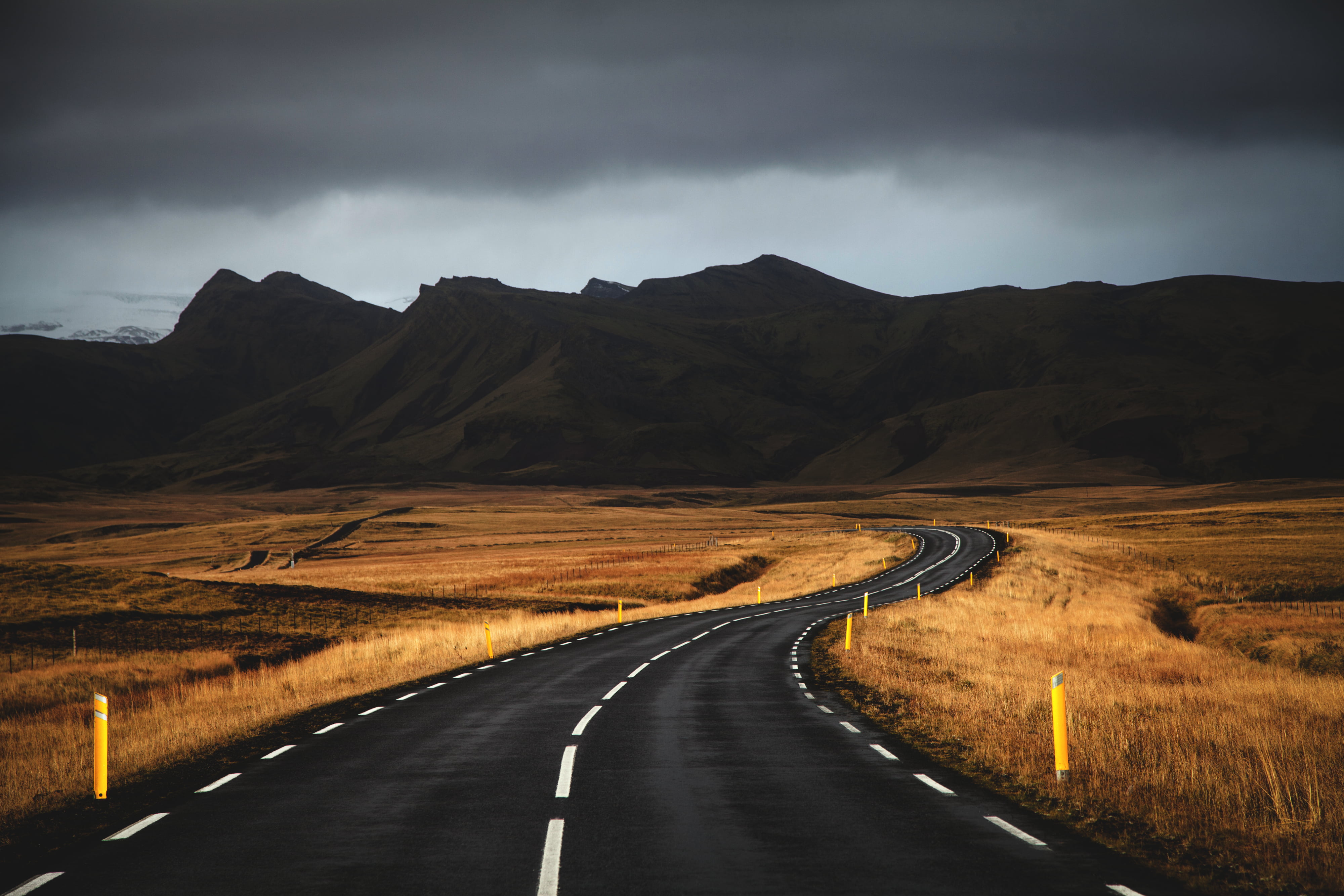 black concrete road near brown grass under cloudy sky