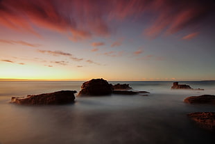 time lapsed of sea and rock formation during golden hour HD wallpaper