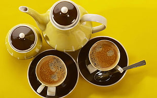 yellow and black ceramic teapot and cups with saucers