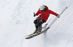 person with red bubble hoodie skiing on slope surface