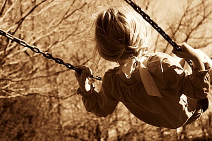 girl wearing gray long sleeve dress riding on swing during daytime