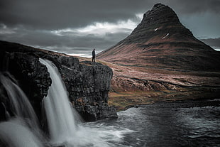 man standing in front of water falls
