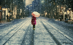 woman wearing pink coat while holding pink umbrella during snow