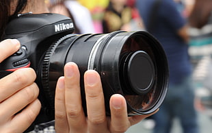 person holding black Nikon DSLR camera HD wallpaper