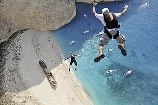 two men diving on cliff at daytime