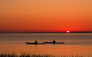 silhouette of two fisherman during sunset