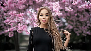 woman wears black crew-neck long-sleeved tops beside pink cherry blossoms tree during daytime HD wallpaper