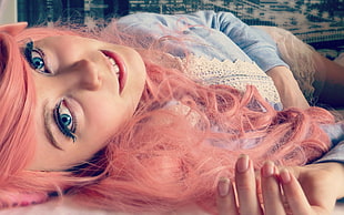 woman in blue and white lace long sleeve shirt with pink colored hair lying on bed