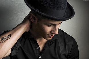 man in black button-up t-shirt wearing black cowboy hat