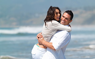 man and woman hugging near body of water during daytime