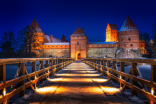 photo of bridge hallway to bricked castle during night time, trakai