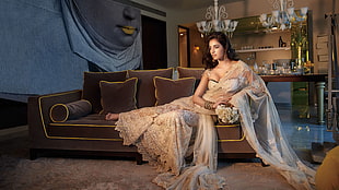 woman wearing white saree while sitting on sofa