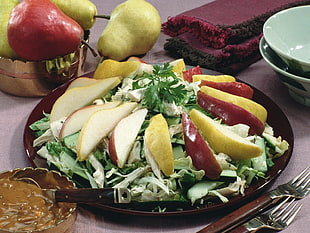 sliced apples and pears on top of green veggies