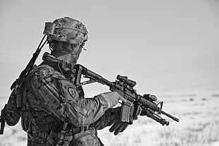 soldier holding rifle grayscale photo