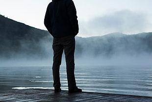 silhouette of man standing in front of foggy lake