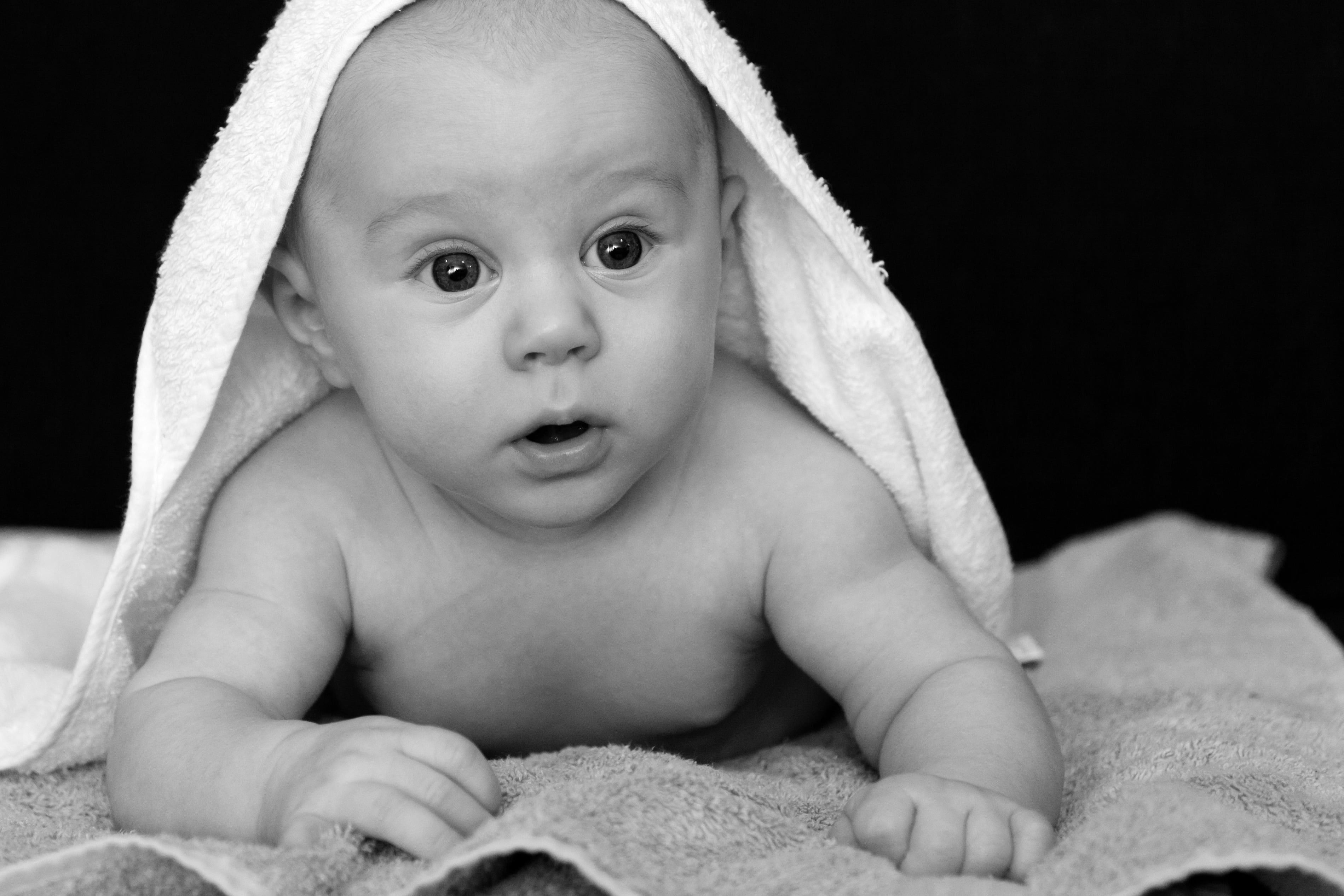 baby covered by towel grayscale photo