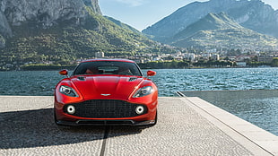 red Aston Martin car parked near body of water