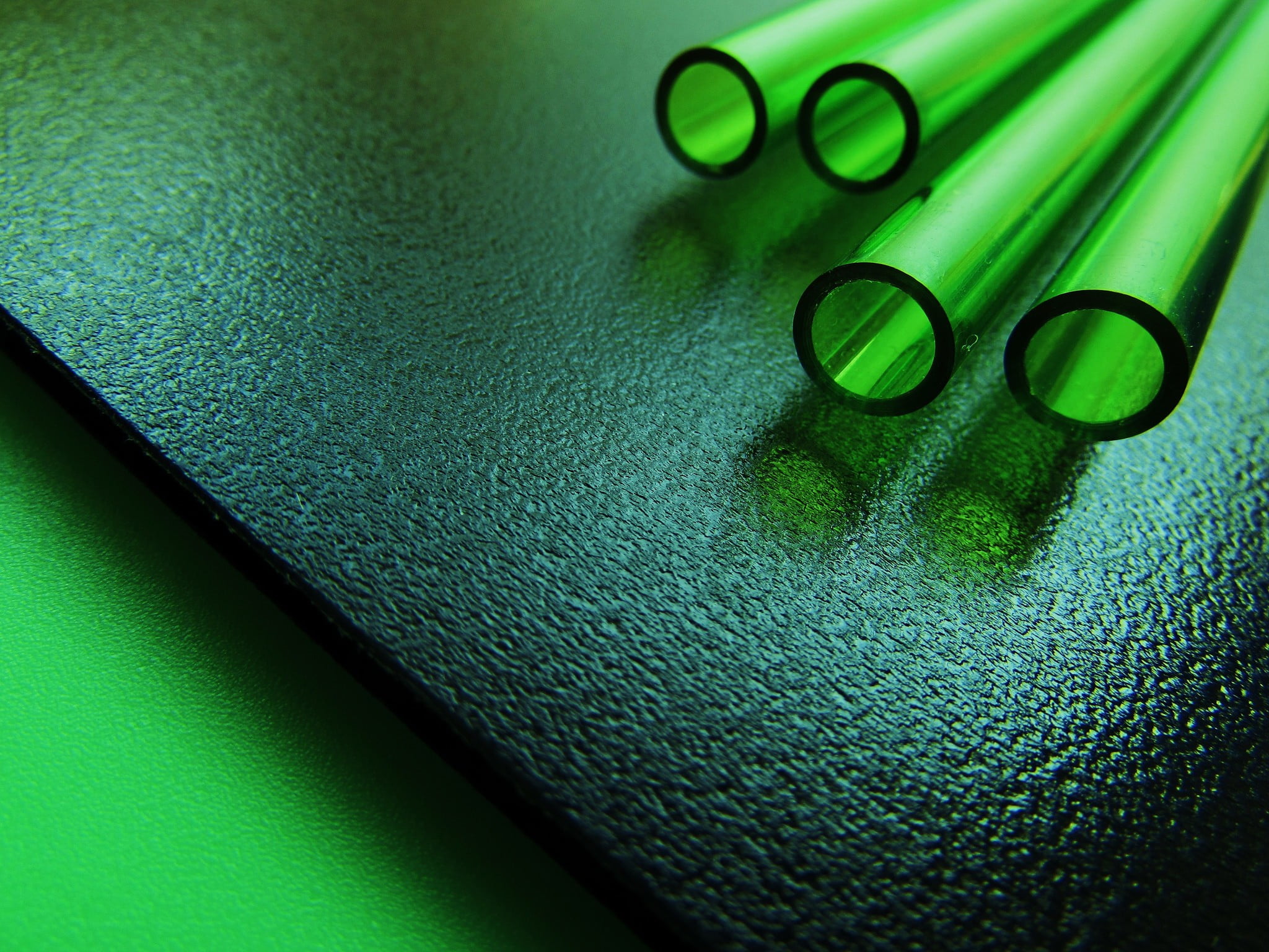 four green tubes on black wooden board, glass, pipes, pattern, reflection