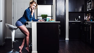 woman in blue long-sleeved shirt and gray boy shorts near wooden table