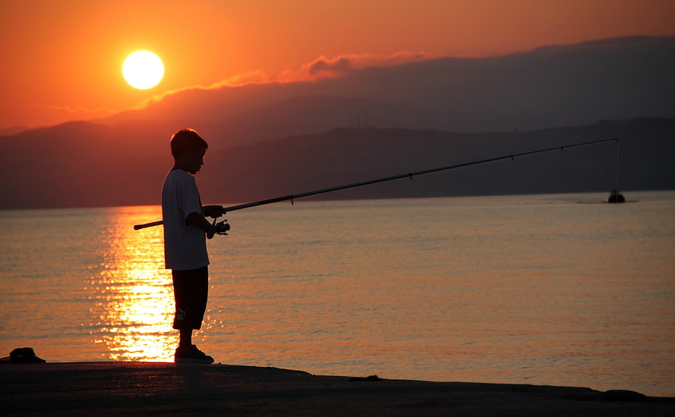 boy holding a fishing rod during sunset HD wallpaper