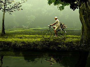 photo of man wearing white clothes riding bicycle in forest