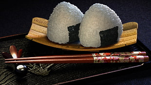 two white rice with brown chop sticks and brown ceramic plates