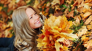 woman laying on the ground and surrounded by leafs