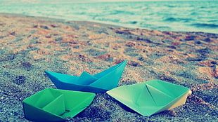 three paper boats on sand during daytime