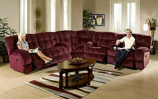 man and woman sitting on red sofa