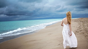 woman in white dress walking on seashore under cloudy sky HD wallpaper