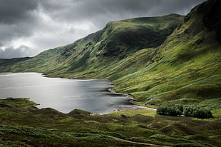 panorama photography of calm body of water surrounded with green hills