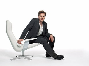 man in black suit sitting on white armchair