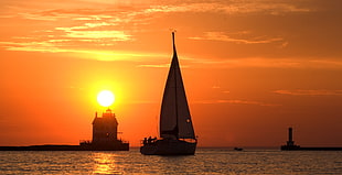 silhouette of sailboat on the ocean near house during golden hour, lorain