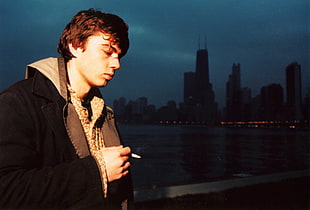 man holding lighted cigarette wearing black coat HD wallpaper