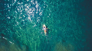 aerial photography of woman on yellow surfboard at sea