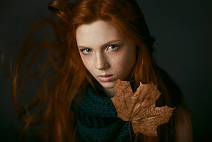 woman holding brown maple leaf