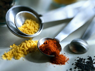 brown and yellow powders on grey metal measuring spoons