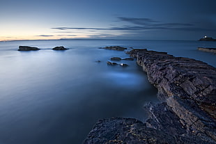 rocky shore on body of water during daytime HD wallpaper